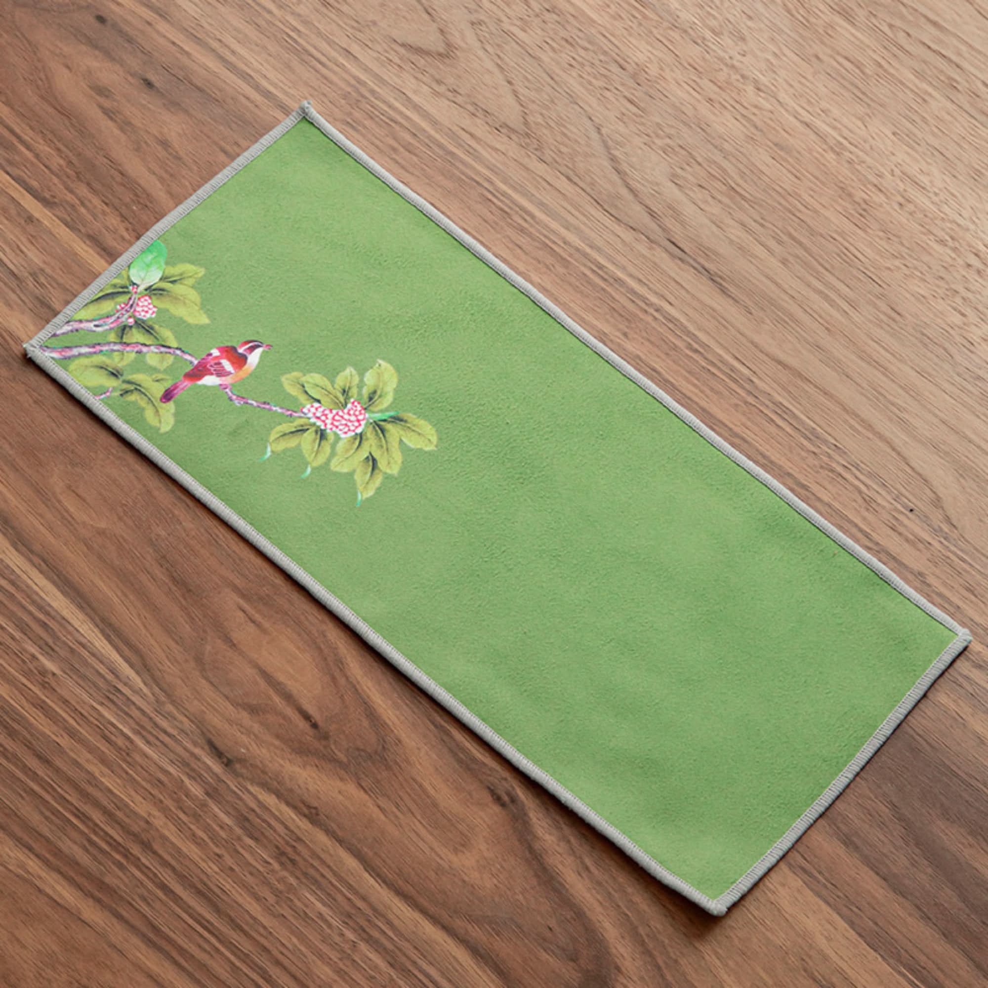 Ukiyo-e Japanese tea towel with bird and floral design on green fabric, on wooden surface.